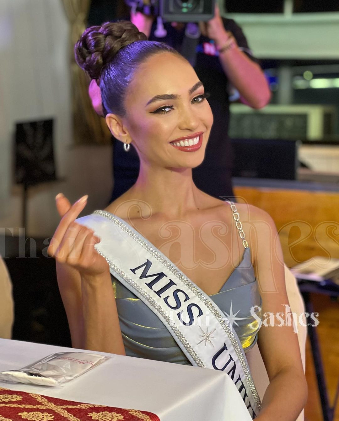 Hoa hậu Hoàn vũ 2022 R'Bonney Gabriel diện bộ váy hai dây tông màu xanh nhạt thanh lịch. Cô chọn kiểu búi tóc cao để khoe chiếc cổ cao thanh lịch và xương quai xanh.