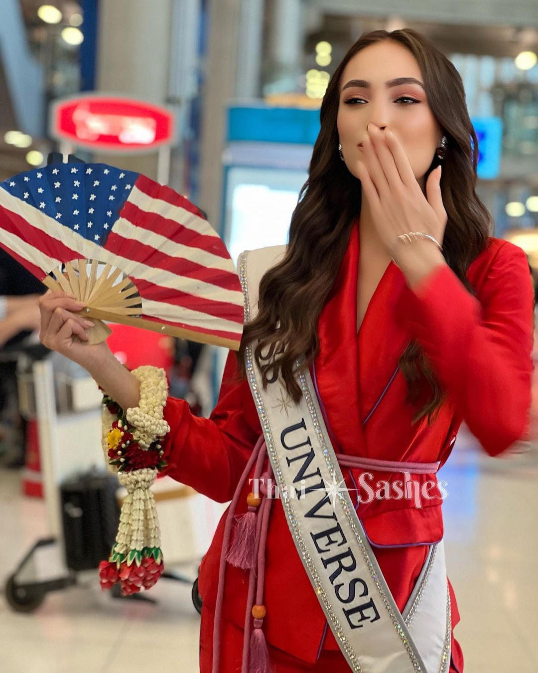 Xuất hiện ở sân bay, người đẹp Mỹ diện bộ trang phục tông màu đỏ kín đáo, sang trọng. Cô gửi nụ hôn gió tới các fan đến sân bay để chào đón mình. R'Bonney Gabriel được yêu mến ở Đông Nam Á vì cô là người đẹp gốc Á, lai Mỹ - Philippines.