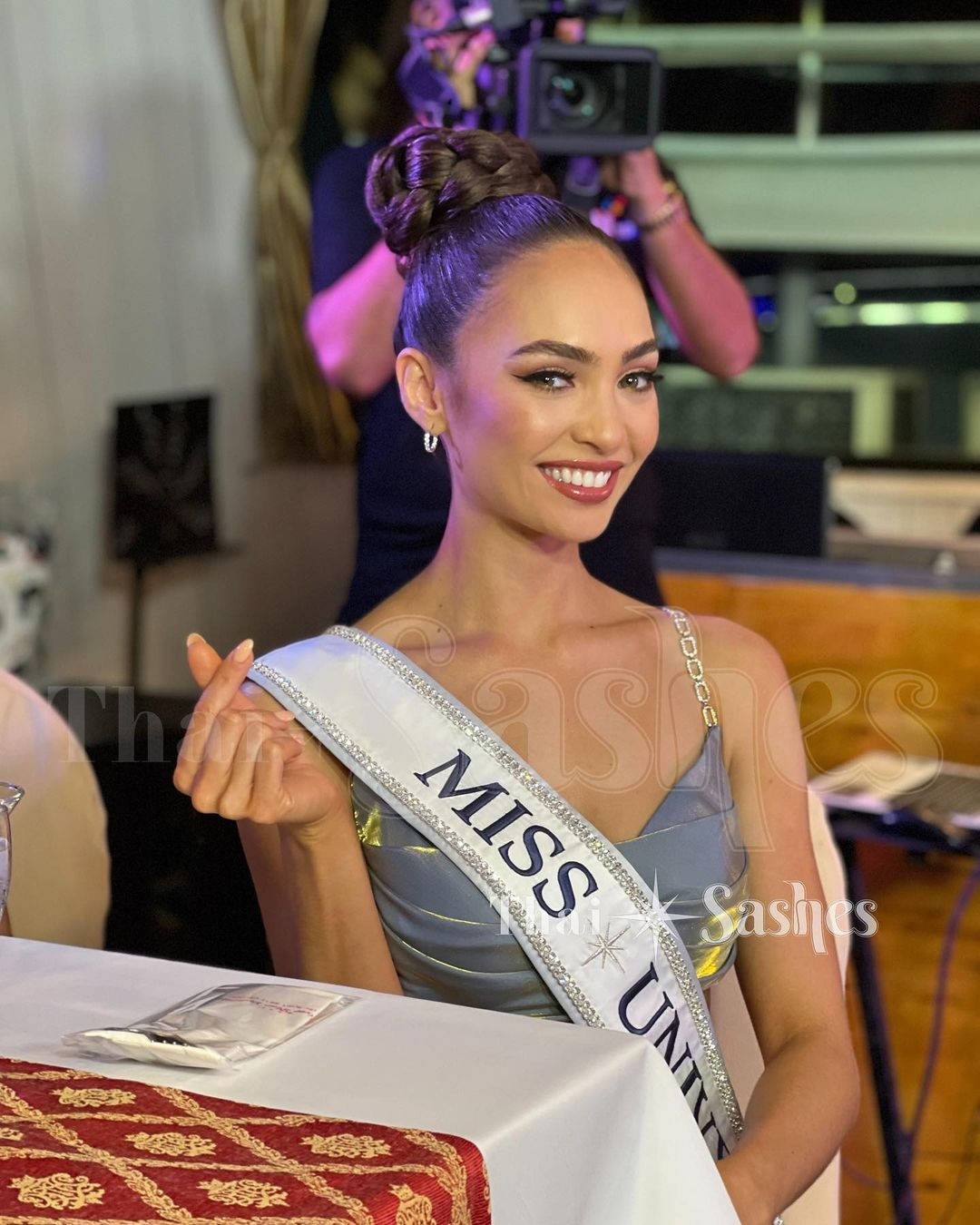 Hoa hậu Hoàn vũ 2022 R'Bonney Gabriel diện bộ váy hai dây tông màu xanh nhạt thanh lịch. Cô chọn kiểu búi tóc cao để khoe chiếc cổ cao thanh lịch và xương quai xanh.