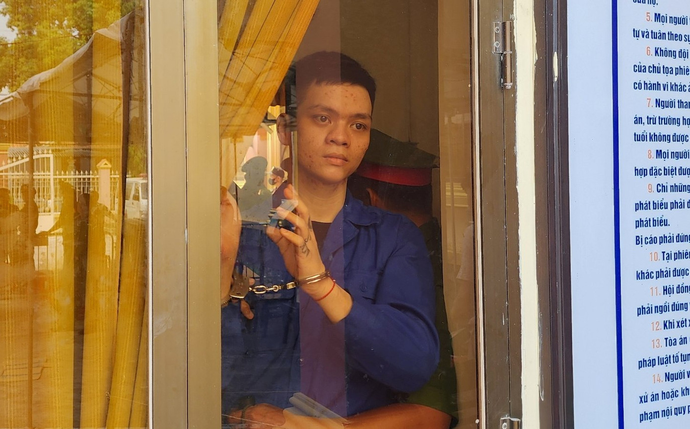 Sau khi bị tuyên tử hình, từ phòng xử án, bị cáo Đoàn Thiên Long kéo màng cửa kính để chào người thân trong lúc chờ dẫn ra xe đưa về trại giam.