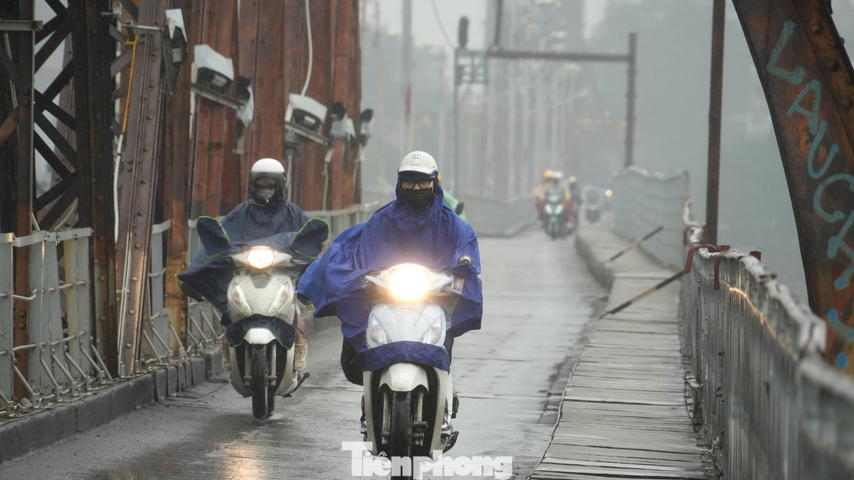 Xe máy đi trên cầu Long Biên thời điểm giữa trưa vẫn phải bật đèn vì thời tiết tối sầm. Dự báo hình thái thời tiết mưa nhỏ, mưa phùn, sương mù sẽ kéo dài đến 15/3.