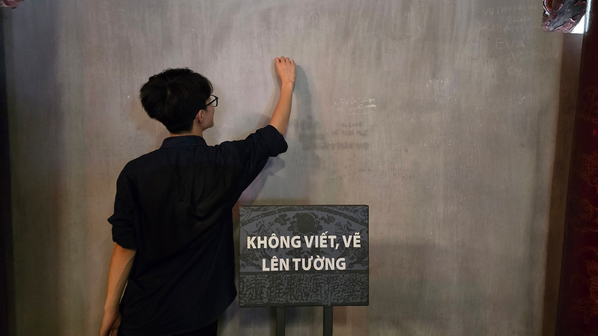 Một số bạn trẻ "viết trong tưởng tượng" những ước nguyện của mình trước kỳ thi trên tường của Văn Miếu.