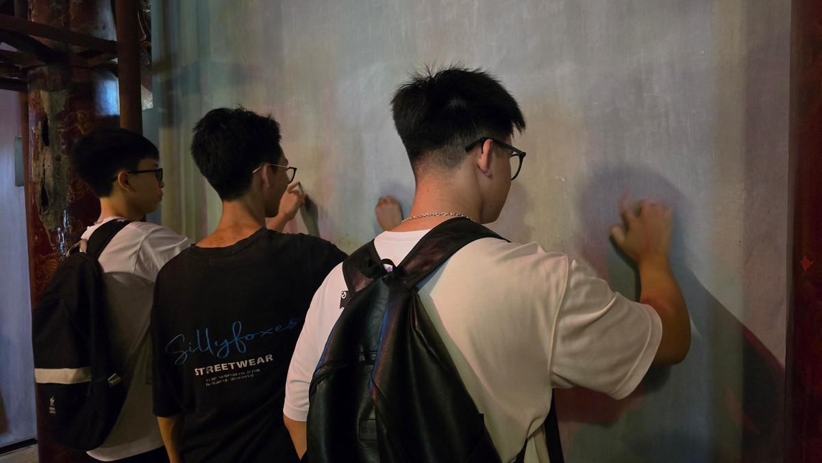 Một số bạn trẻ "viết trong tưởng tượng" những ước nguyện của mình trước kỳ thi trên tường của Văn Miếu.