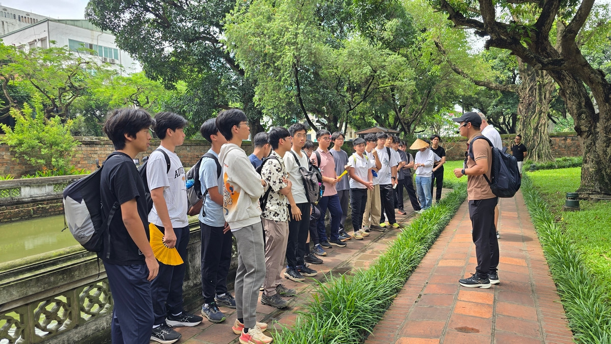 Một lớp học sinh trường quốc tế đang được hướng dẫn viên giới thiệu về Văn Miếu Quốc Tử Giám.