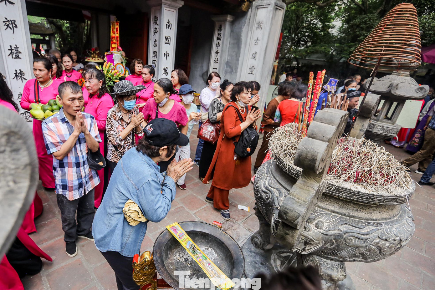 Ngoài sân, người người đến chiêm bái, vái vọng.