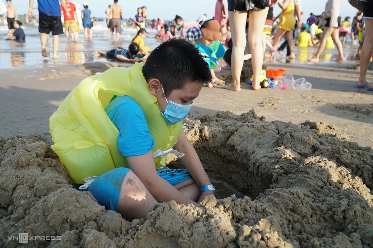 Nguyễn Nhật Thanh, 7 tuổi, đào hố cát. Suốt buổi chiều hôm nay, cậu bé không cởi khẩu trang. "Mẹ con và cô giáo bảo phải đeo để vừa bảo vệ cho mình, cho mọi người tránh Covid -19", bé trai nói. Nguyễn Nhật Thanh, 7 tuổi, đào hố cát. Suốt buổi chiều hôm nay, cậu bé không cởi khẩu trang. "Mẹ con và cô giáo bảo phải đeo để vừa bảo vệ cho mình, cho mọi người tránh Covid -19", bé trai nói.