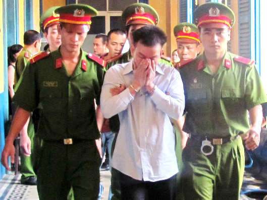  Trình Văn Tám che mặt khi bị dẫn giải ra xe