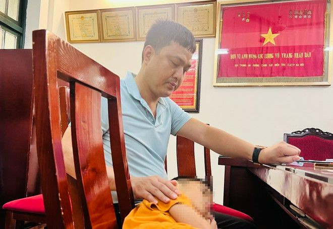 Phút bình yên của bé Ken và bố tại trụ sở cơ quan công an. Ảnh Thùy An.