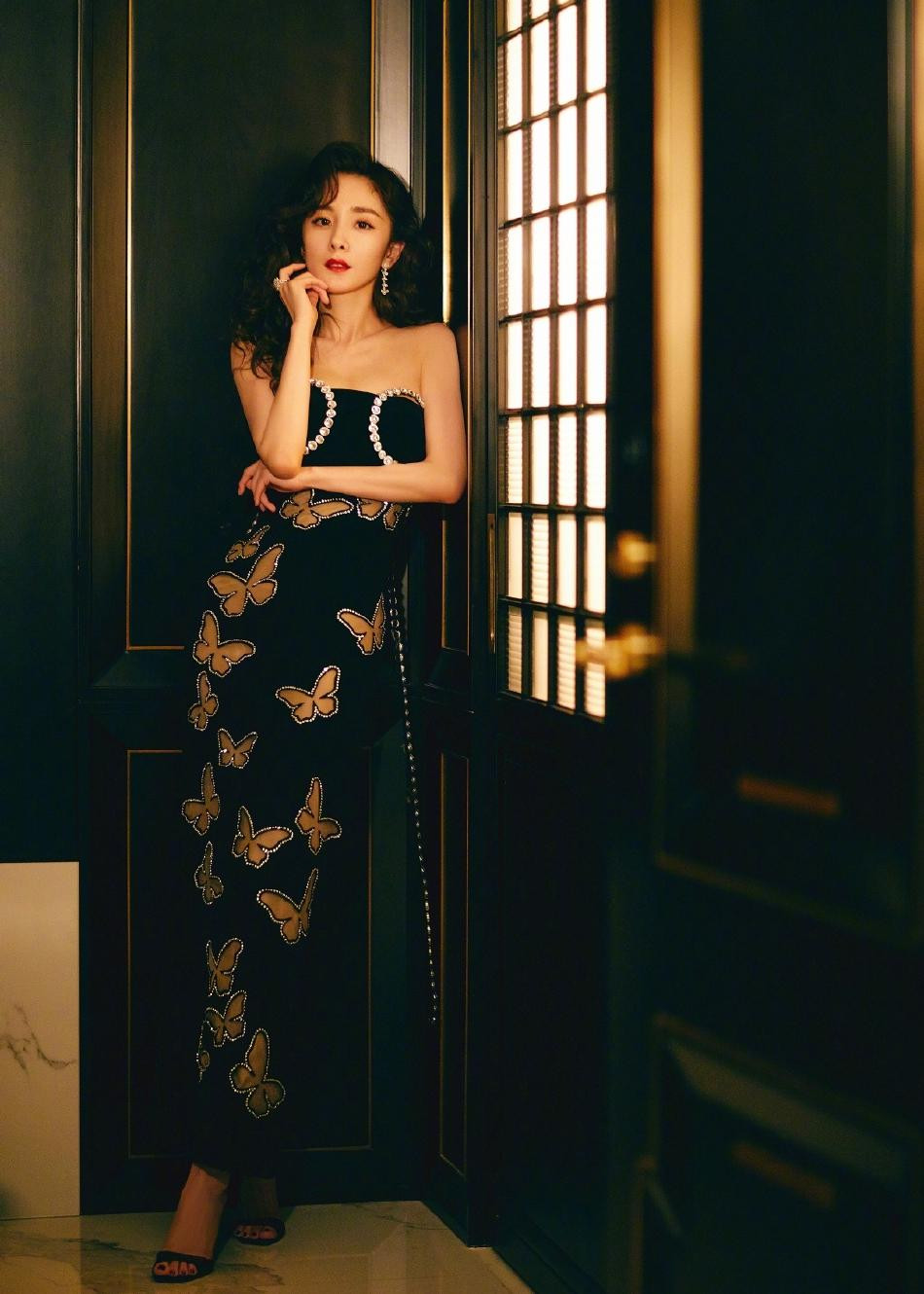 Trong bộ ảnh, nàng "tiểu hoa đán" 8x mặc váy quây đen dài với những hình cắt bươm bướm xuyên thấu có viền đính đá lấp lánh, kết hợp với sandal cao gót "ton-sur-ton".