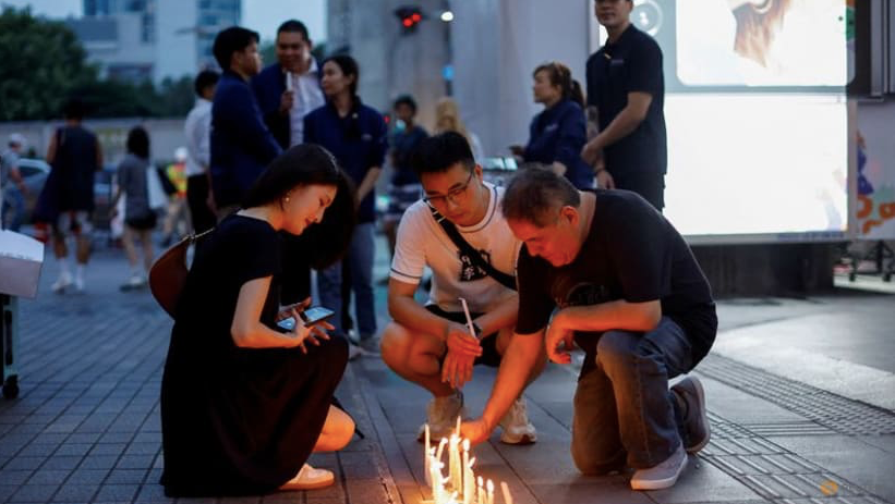 Một số người thắp nến bên ngoài trung tâm thương mại Siam Paragon sau vụ xả súng ngày 4/10. (Ảnh: Reuters)