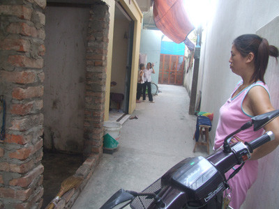 Chị Thơm đứng trước buồng chứa củi (có hai cột gạch không trát vữa), nơi phát hiện ổ bọ xít trên 1.000 con. 