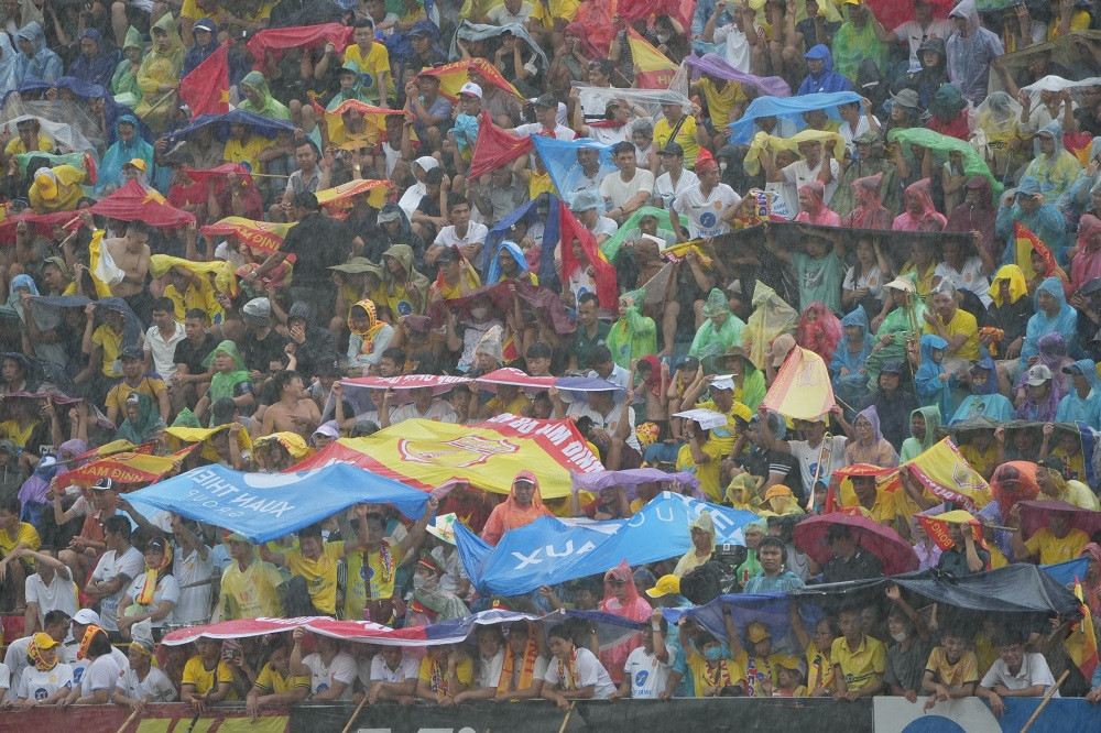 Cổ động viên dùng băng rôn, cờ CLB để che mưa. Ảnh: Mạnh Thắng