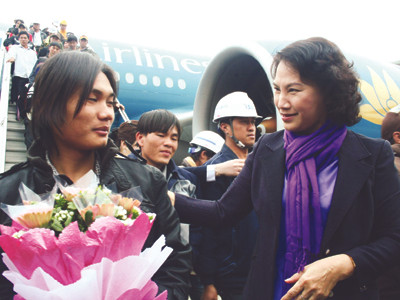 Bộ trưởng Nguyễn Thị Kim Ngân tặng hoa cho lao động sau khi xuống máy bay, sáng qua Ảnh: Đình Thắng