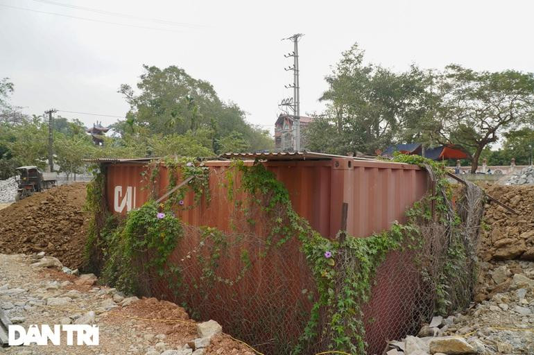 Sau một thời gian dài nằm phơi mưa phơi nắng, thùng container đựng lô gỗ sưa "trăm tỷ" hoa cỏ quấn xung quanh, giờ nằm lọt thỏm dưới nền đất nhà văn hóa thôn Phụ Chính (Ảnh: Trọng Trinh).