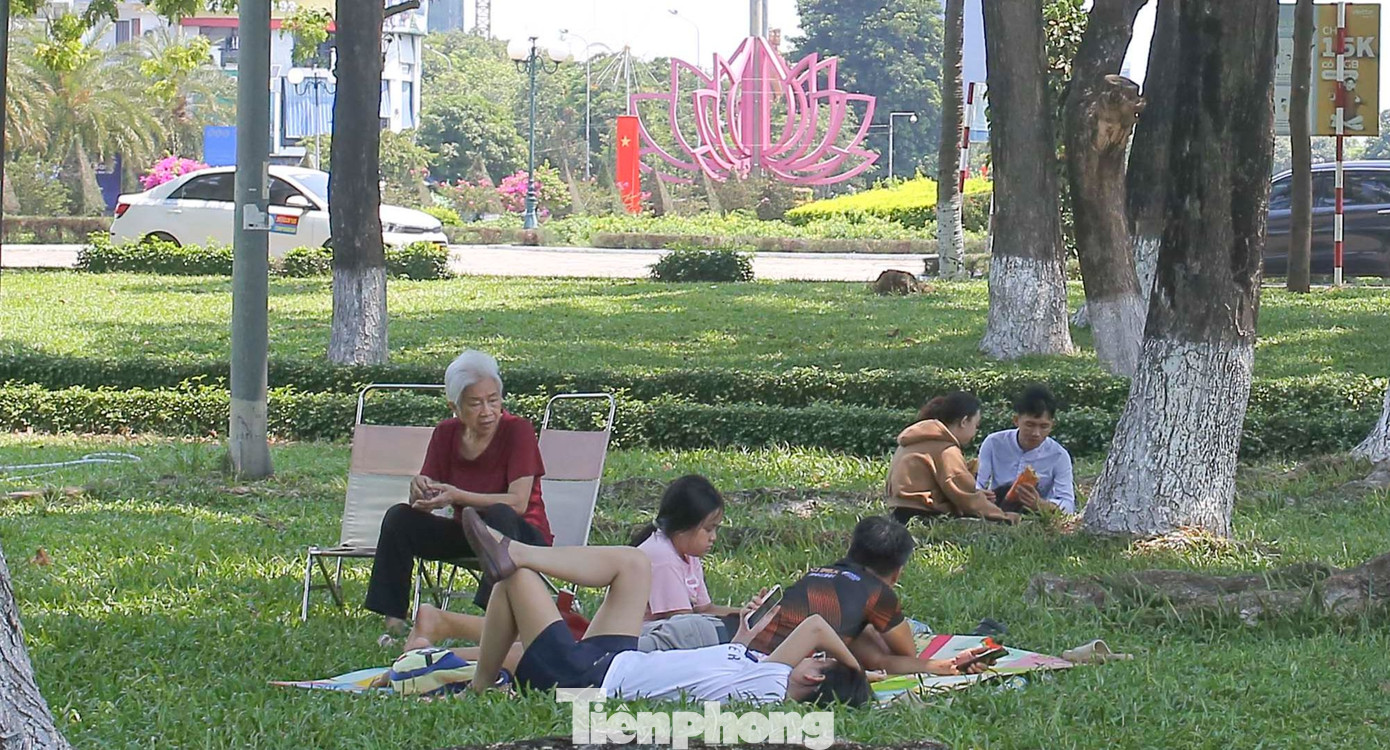 Nhiều người mang theo ghế, chiếu trải lên thềm cỏ, mắc võng vào cây lớn để nghỉ ngơi; tổ chức ăn uống dưới những gốc cây lớn có bóng mát. Ảnh: Trương Định.