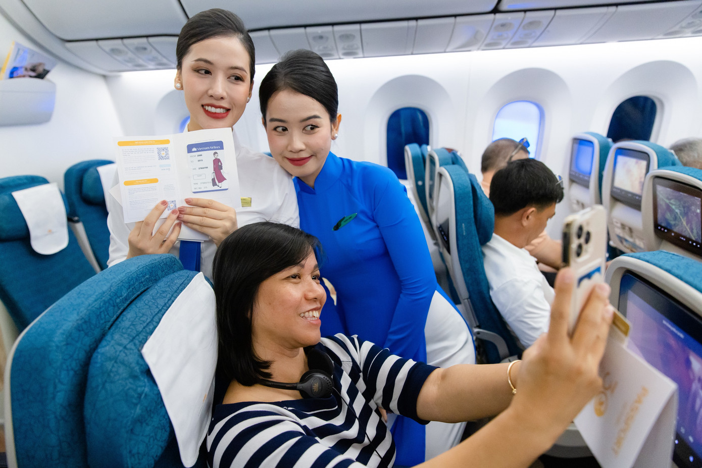 Hành khách thích thú khi nhận được những phần quà đặc biệt và lưu lại hình ảnh cùng với tiếp viên trong đồng phục các thời kỳ của Vietnam Airlines. Ảnh: VNA.