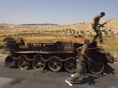 Hai binh sĩ nổi dậy cạnh xác xe tăng của quân chính phủ. Ảnh: ABC News