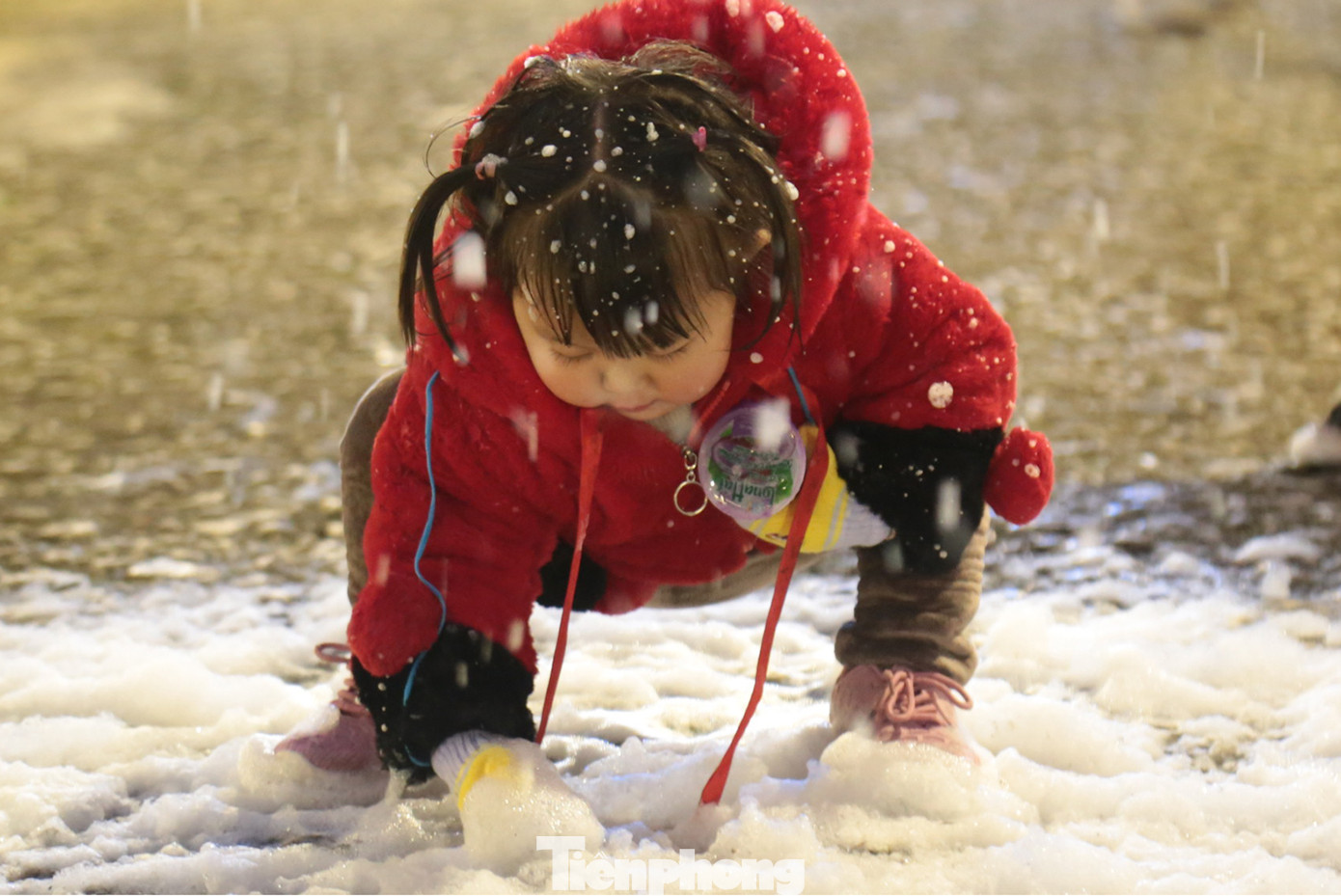 Em bé chơi đùa với bọt tuyết một cách say sưa.