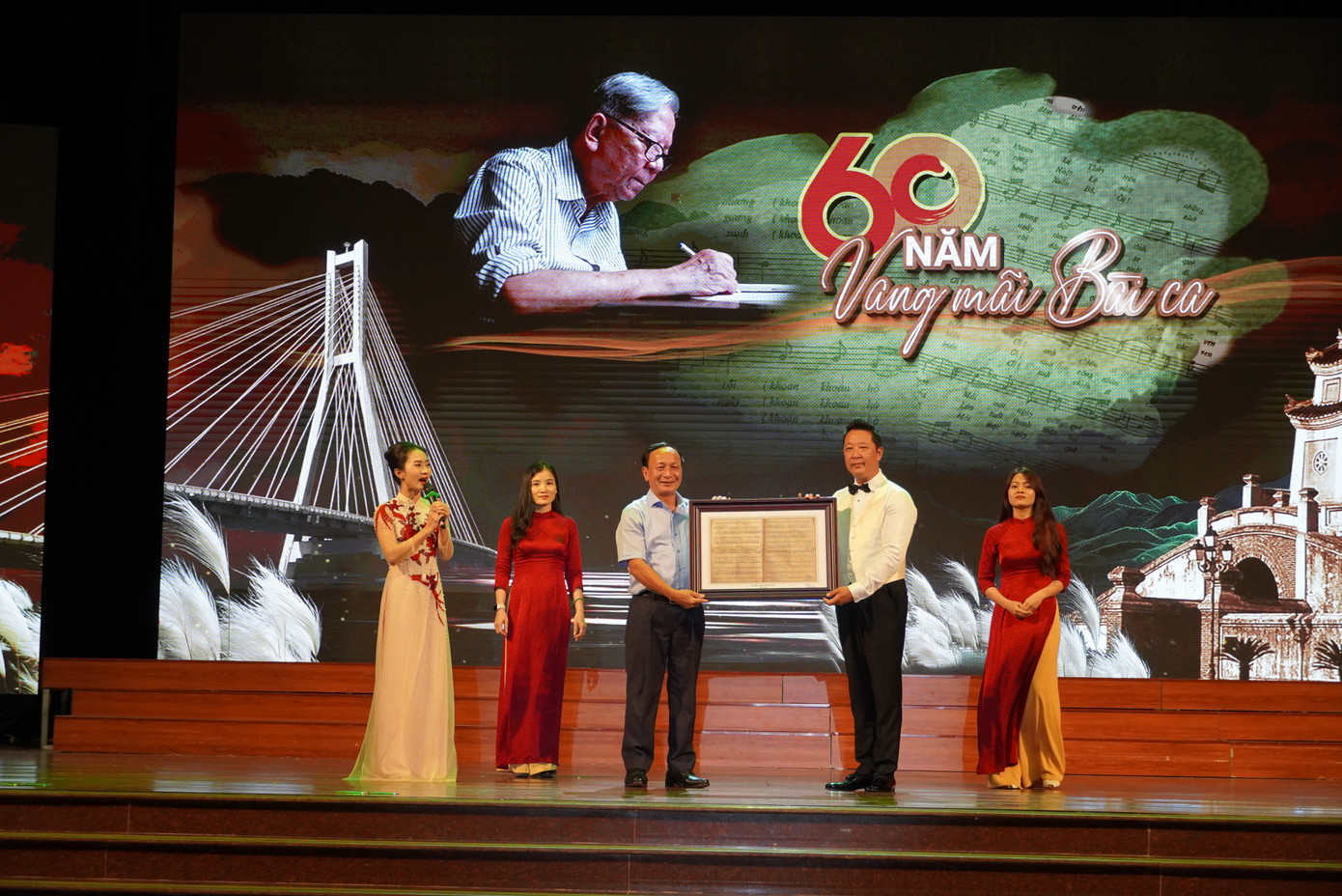 Nhạc trưởng Lê Phi Phi thay mặt gia đình trao bản gốc ca khúc "Quảng Bình quê ta ơi!" tặng tỉnh Quảng Bình trong đêm nhạc "60 năm vang mãi bài ca".