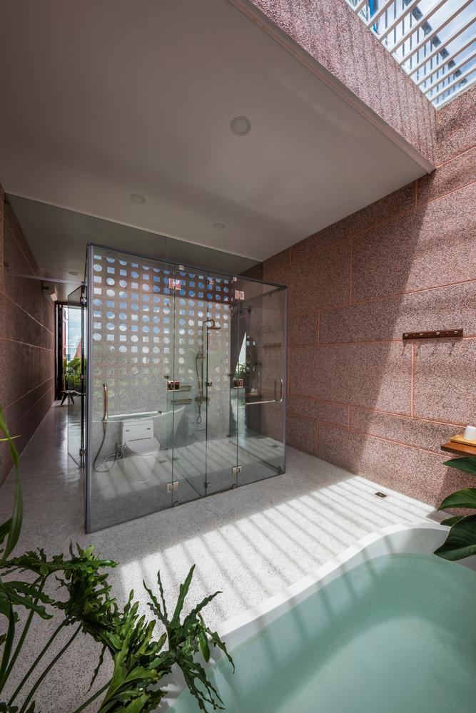 Phòng tắm có bồn lớn và khu vệ sinh bằng kính trong suốt.