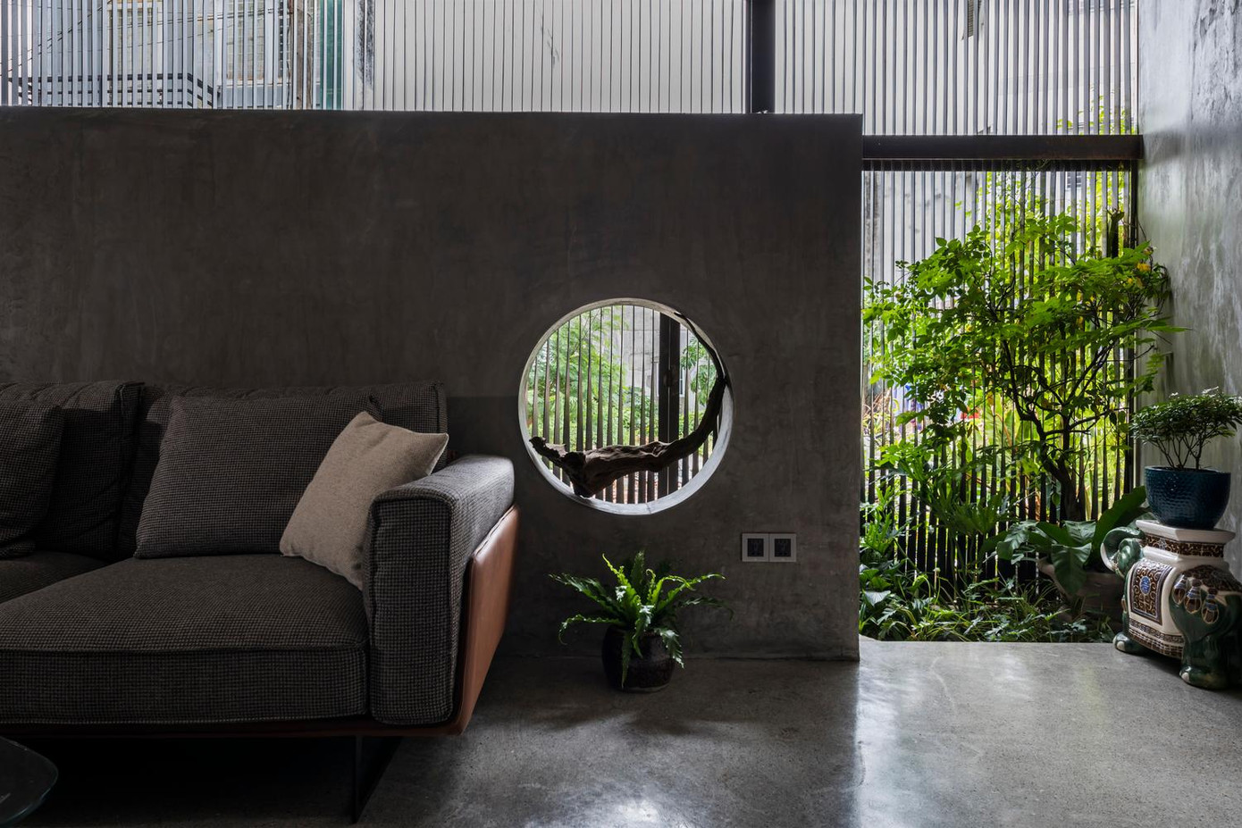 Sàn nhà được xây cao hơn mặt đường để tránh ngập úng. Tiền sảnh rộng rãi làm chỗ để xe và trồng nhiều cây xanh để tạo lớp đệm chống nắng cho bên trong. Thay vì thiết kế lối vào ở chính giữa thì ngôi nhà này để cửa ở góc bên trái, muốn lên tầng trệt cần bước qua bệ đá giống như bước vào một hang động để khám phá. Sàn nhà được xây cao hơn mặt đường để tránh ngập úng. Tiền sảnh rộng rãi làm chỗ để xe và trồng nhiều cây xanh để tạo lớp đệm chống nắng cho bên trong. Thay vì thiết kế lối vào ở chính giữa thì ngôi nhà này để cửa ở góc bên trái, muốn lên tầng trệt cần bước qua bệ đá giống như bước vào một hang động để khám phá.