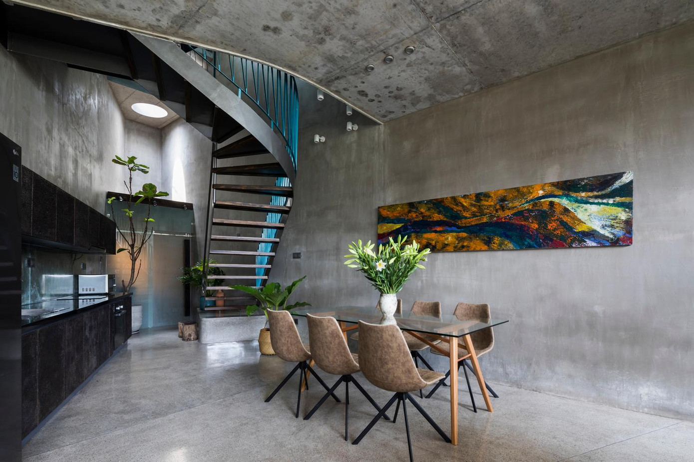 Tại tầng trệt, tủ bếp được làm ép sát tường phía trái, cạnh đó là tủ lạnh và ti vi. Chính giữa là bàn ăn và một bộ sofa tiếp khách. Để đảm bảo sự riêng tư và cách nhiệt cho gia chủ ở tầng trệt, các kiến trúc sư cho xây dựng một tấm chắn bằng bê tông dày có khoảng mở hình tròn cạnh bộ sofa để người trong nhà vẫn quan sát được phía ngoài đường. Tại tầng trệt, tủ bếp được làm ép sát tường phía trái, cạnh đó là tủ lạnh và ti vi. Chính giữa là bàn ăn và một bộ sofa tiếp khách. Để đảm bảo sự riêng tư và cách nhiệt cho gia chủ ở tầng trệt, các kiến trúc sư cho xây dựng một tấm chắn bằng bê tông dày có khoảng mở hình tròn cạnh bộ sofa để người trong nhà vẫn quan sát được phía ngoài đường.