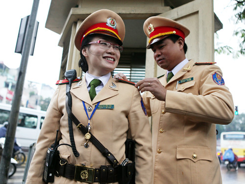 Ngày đầu làm việc, dù trời mưa rét, các nữ cản sát giao thông tự tin làm việc giữa phố đông. Trong ảnh là Thiếu tá Trần Quang Vinh - Đội phó Đội Cảnh sát Giao thông số 1, đang giúp Trung úy Hoàng Thị Cẩm Vân trước giờ làm nhiệm vụ. Ảnh: Xuân Phú.