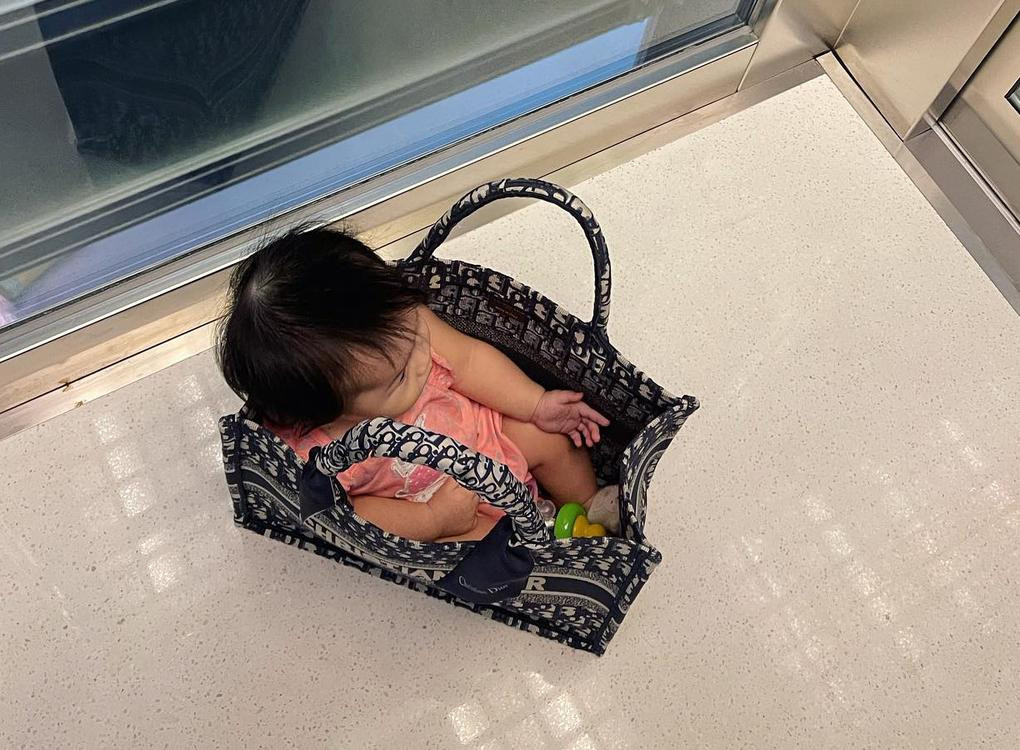 Cô bé ngồi lọt thỏm trong túi xách của mẹ.