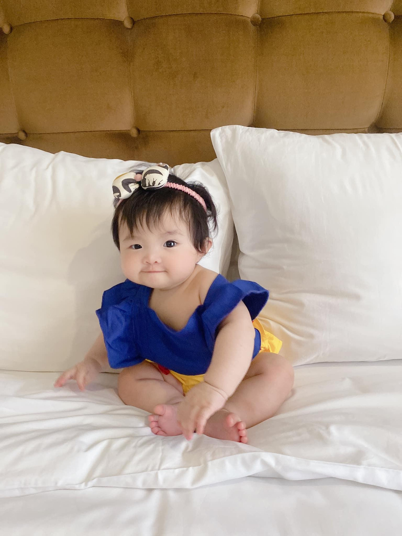 Con gái cặp sao được đặt ngồi trên giường, ra dáng người lớn.