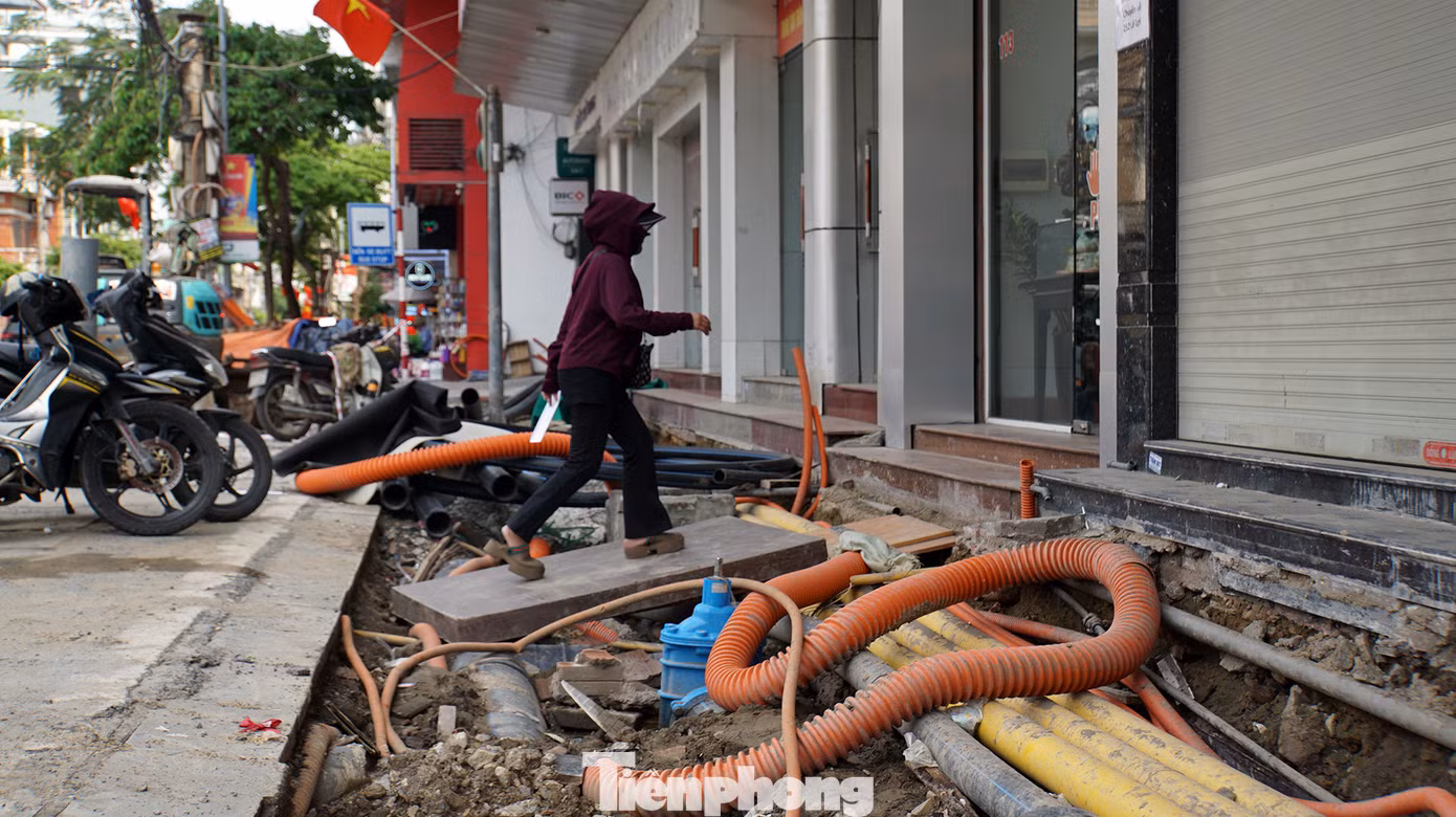 Các hộ dân, hộ kinh doanh đặt ván gỗ hoặc các vật liệu bắc cầu từ lòng đường vào nhà, phía dưới là hệ thống đường điện, cáp viễn thông, cống thoát nước...