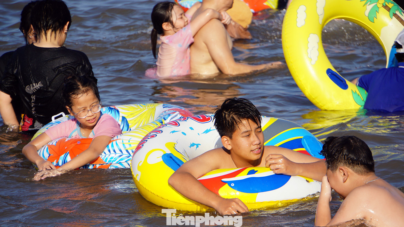 Các em nhỏ nô đùa bên bờ cát, ôm phao tắm biển. Các em nhỏ nô đùa bên bờ cát, ôm phao tắm biển.