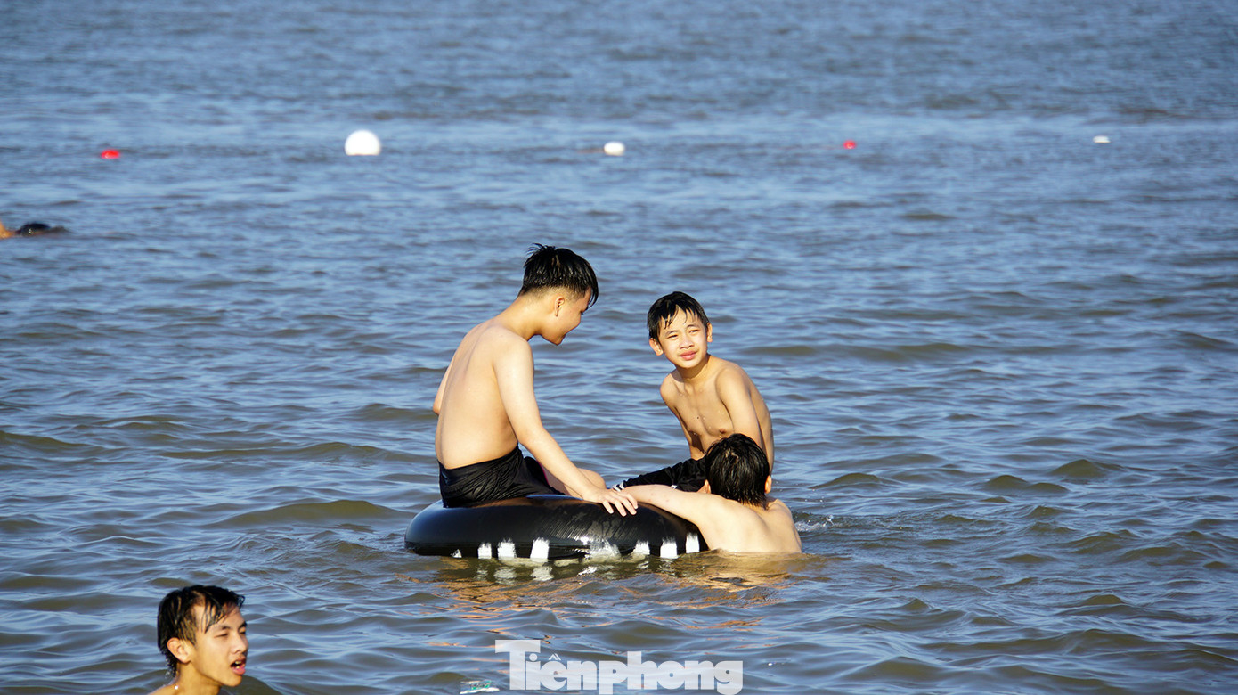 Các em nhỏ nô đùa bên bờ cát, ôm phao tắm biển. Các em nhỏ nô đùa bên bờ cát, ôm phao tắm biển.