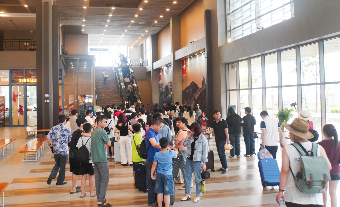 Tại khu vực nhà ga cáp treo, hàng nghìn khách đi theo đoàn, theo nhóm gửi ô tô ở bãi đỗ rồi mua vé đi cáp treo.