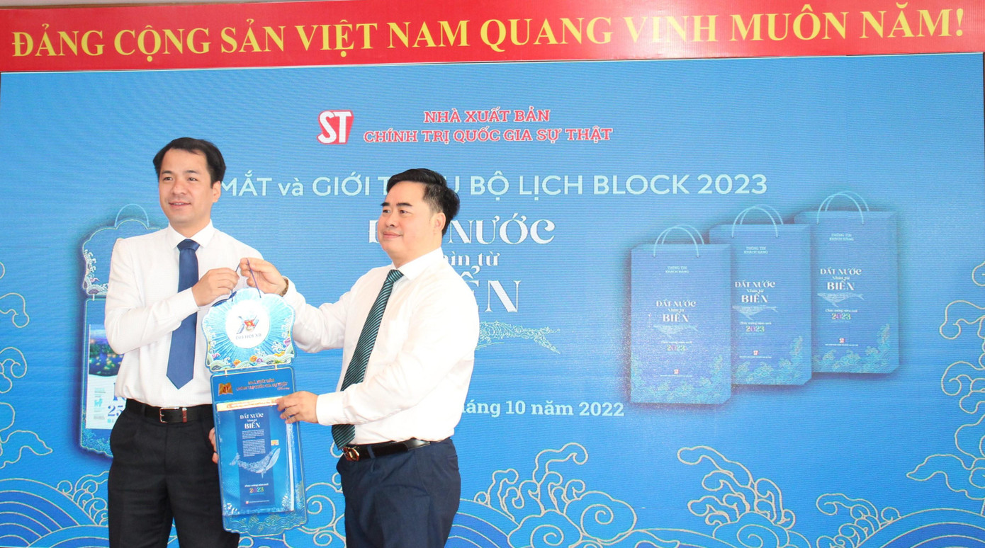 Anh Ngô Văn Cương (trái) tiếp nhận tượng trưng bộ lịch block từ PGS.TS. Phạm Minh Tuấn. Ảnh: THÚY LÊ.