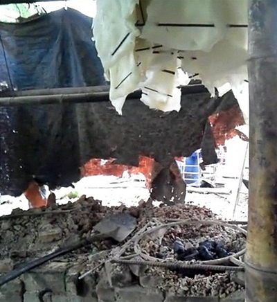 Bì lợn được treo lên bếp than để sấy khô. Phía dưới là chiếc quạt thổi bụi bay mù mịt