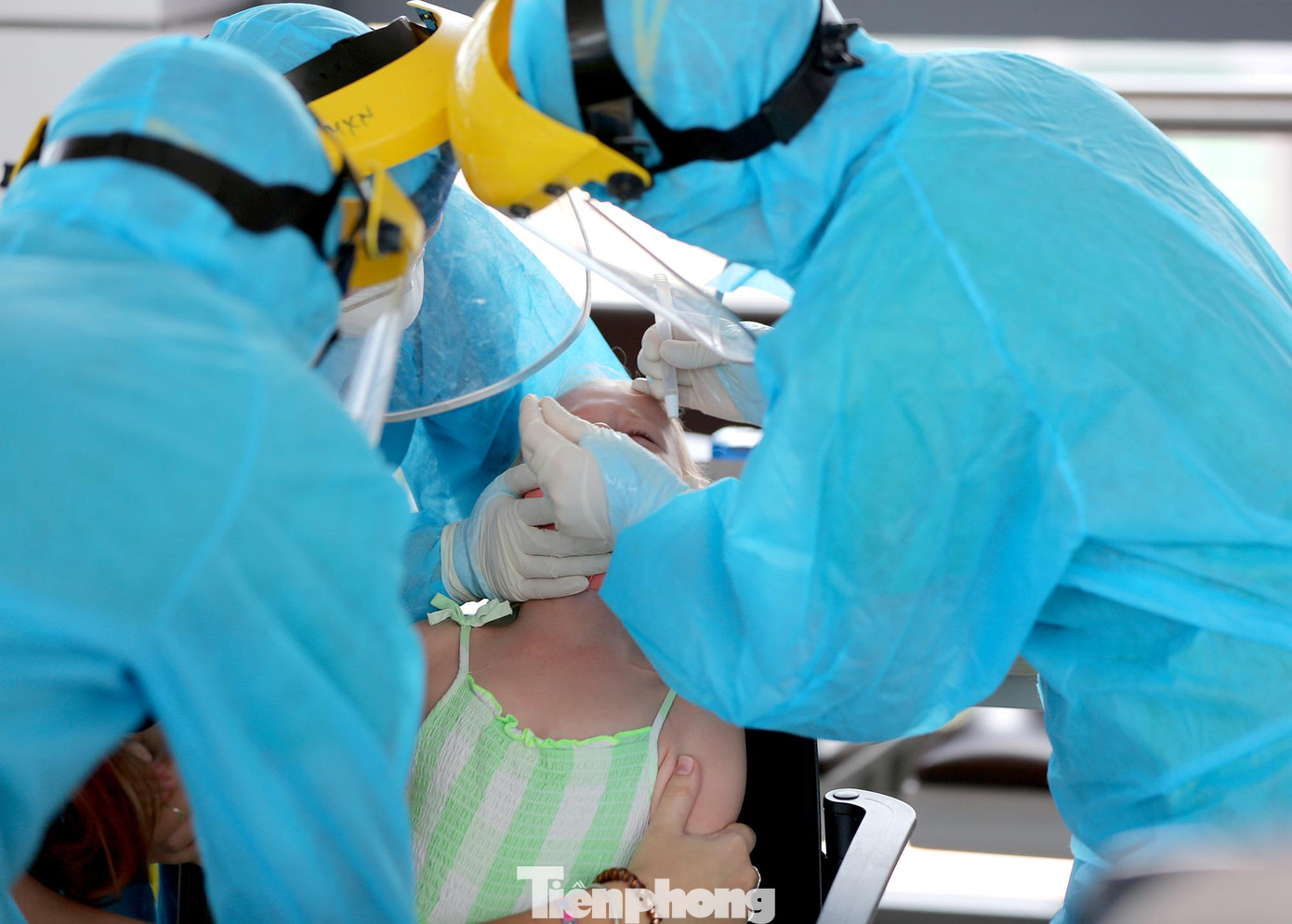 Một hành khách nhí lấy mẫu xét nghiệm trưa ngày 17/7 cần sự hỗ trợ thêm của 2 nhân viên y tế.