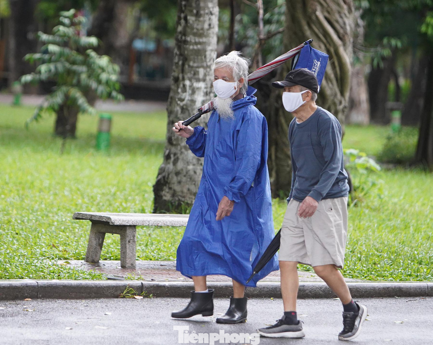 Các cụ già mặc áo mưa hoặc che ô để đi bộ tập thể dục.