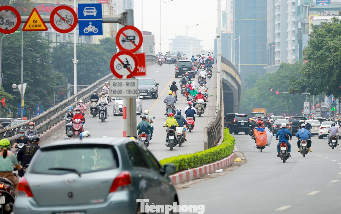 Trục đường Láng Hạ - Lê Văn Lương là nơi có mật độ phương tiện tham gia giao thông rất lớn nhất là vào giờ cao điểm Sở GTVT Hà Nội đã bố trí biển cấm trên cầu vượt Láng Hạ - Thái Hà - Huỳnh Thúc Kháng và cầu vượt đường Láng - Lê Văn Lương. Theo đó, tất cả xe máy bị cấm đi lên hai cầu vượt vào các khung giờ 6h - 9h và 16h30 - 19h30 hàng ngày. Tuy nhiên rất nhiều xe máy vẫn nườm nượp nối đuôi nhau lưu thông qua cầu vượt. Bởi lượng phương tiện vi phạm vào khung giờ cao điểm quá đông, nên lực lượng chức năng chưa thể tổ chức xử lí vi phạm. Người dân vẫn ngang nhiên vi phạm đi lên cầu trong giờ cao điểm, phớt lờ biển báo trên cầu vượt. Chiều 28/4, quan sát chưa đến 15 phút, phóng viên Tiền Phong phát hiện hàng chục xe máy nối đuôi nhau đi lên trên cầu trong khung giờ cấm. Xe máy nối đuôi nhau đi lên cầu theo cả hai hướng.