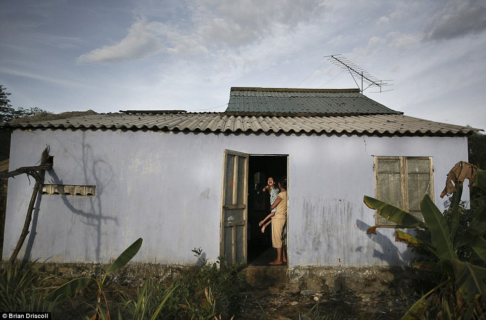 Hương Nghiêm, 8 tuổi, thế hệ thứ ba của nạn nhân chất độc da cam, được mẹ cô bế trước cửa nhà của họ ở huyện Trần Văn Cao, Hội An