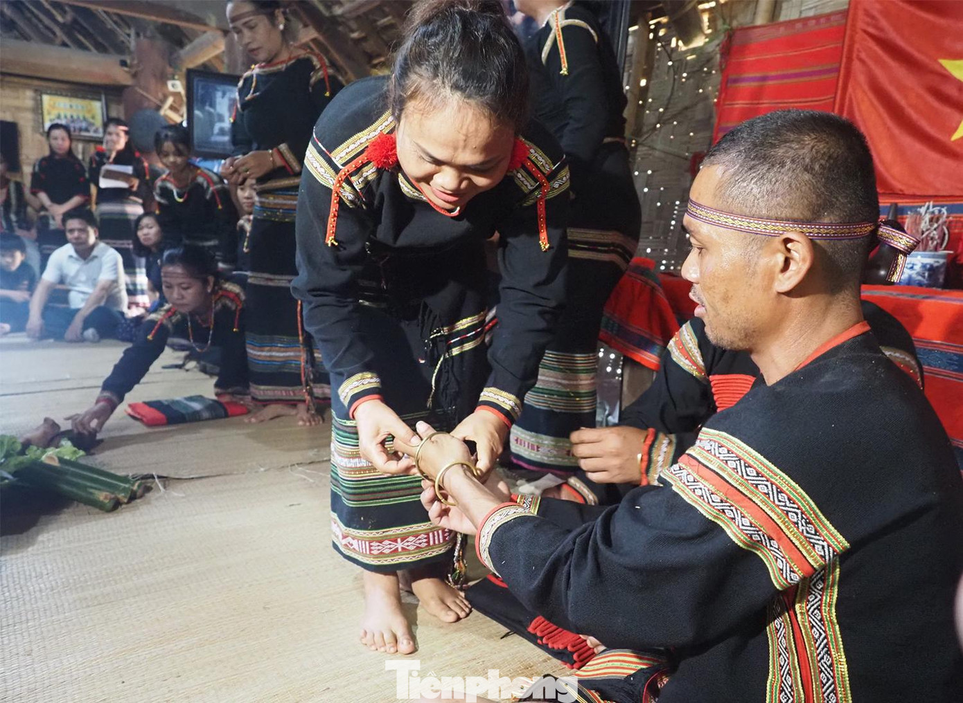 Người nhận con nuôi và người được nhận làm con nuôi cùng chạm tay vào vòng (kông) và hứa trước hai già làng: “Từ nay về sau sẽ coi nhau như mẹ con ruột thịt”. Trong ảnh: Mẹ nuôi đeo chiếc vòng cho con nuôi cùng với lời chúc sức khoẻ, thể hiện tình cảm, sự quan tâm đùm bọc và gắn kết mẹ con.