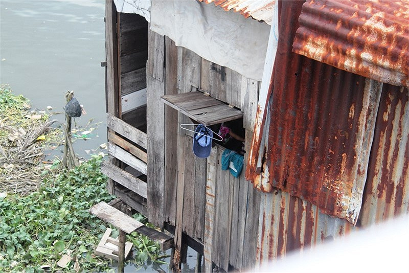 Một em nhỏ đang vui đùa trong căn nhà 'ổ chuột' chông chênh bên bờ kênh