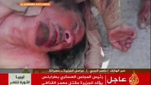 Cơ thể đẫm máu của ông Gaddafi bị kéo lê trên đường.. Cơ thể đẫm máu của ông Gaddafi bị kéo lê trên đường.