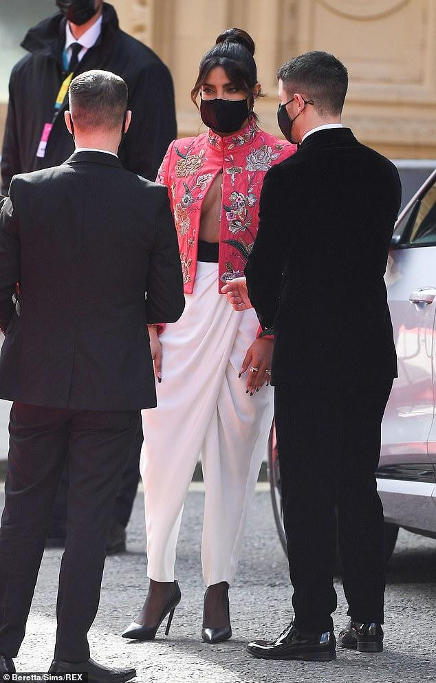 Chiếc áo xẻ ngực táo bạo lộ rõ vòng một căng đầy của mỹ nhân Ấn Độ. Vợ chồng cô đeo khẩu trang tuân thủ biện pháp phòng dịch khi đến sự kiện.