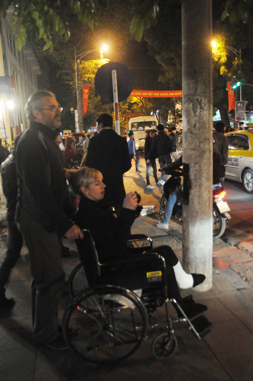 Dù vợ phải ngồi xe lăn nhưng du khách này vẫn quyết tâm đưa vợ mình đi đón giao thừa tại Hà Nội