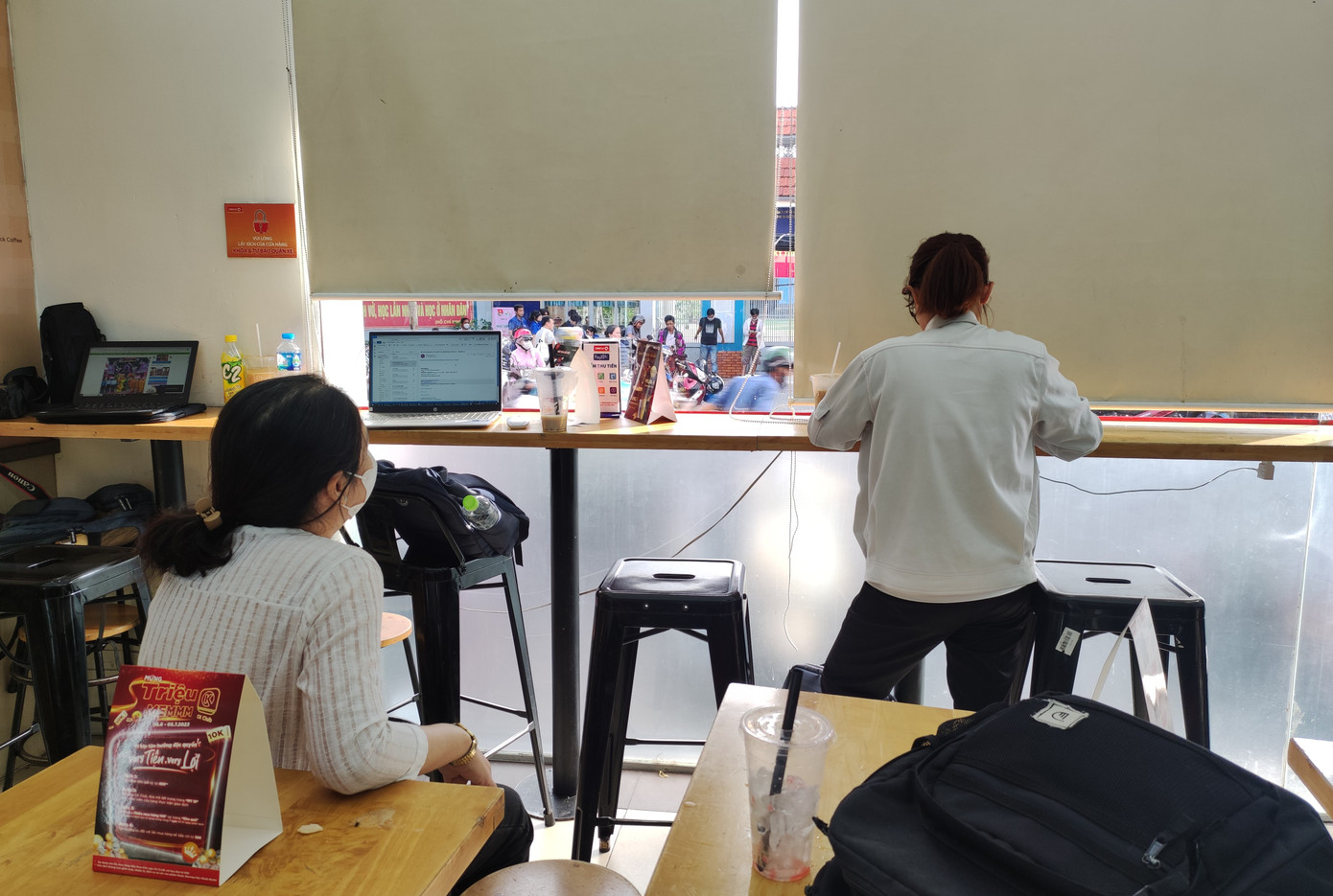 Người mẹ mang theo máy tính làm việc và dõi theo vào nơi con mình đang làm bài.