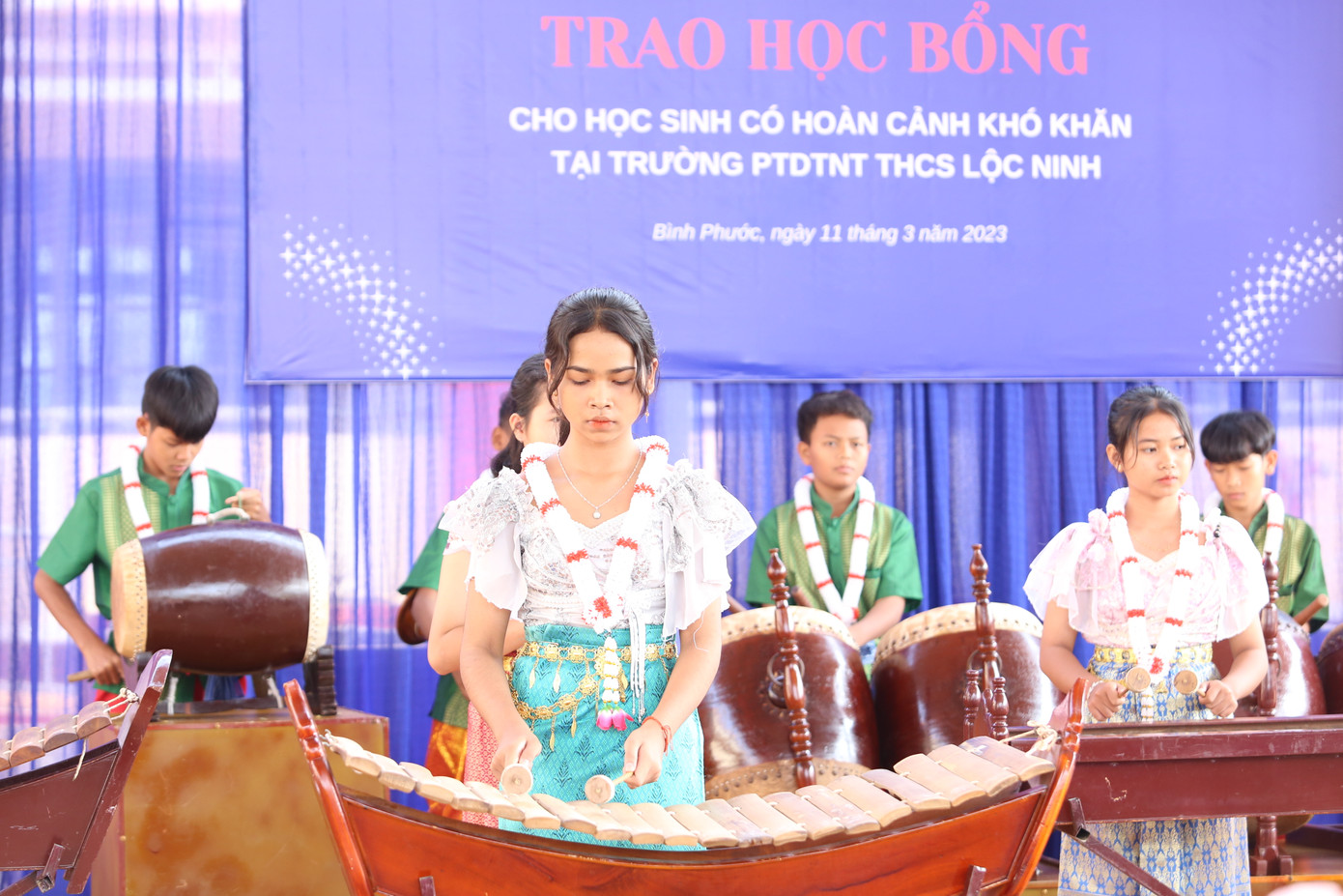 Các em học sinh nhà trường chào đón đoàn bằng tiết mục biểu diễn cùng các nhạc cụ truyền thống. Ở trường, 100% học sinh được học chơi các loại nhạc cụ như trống, đàn T'rưng...