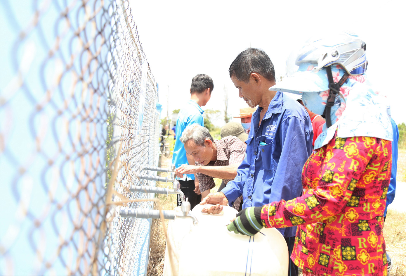 Người dân Phú Đông phấn khởi đón nhận những bình nước đầu tiên từ hệ thống.