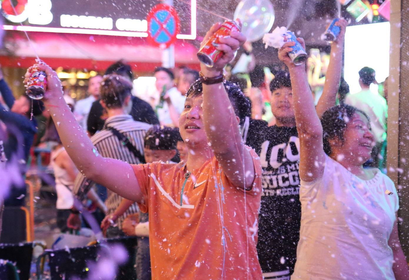 Người dân phun bọt tuyết trắng xóa không gian phố đi bộ chào mừng năm mới.