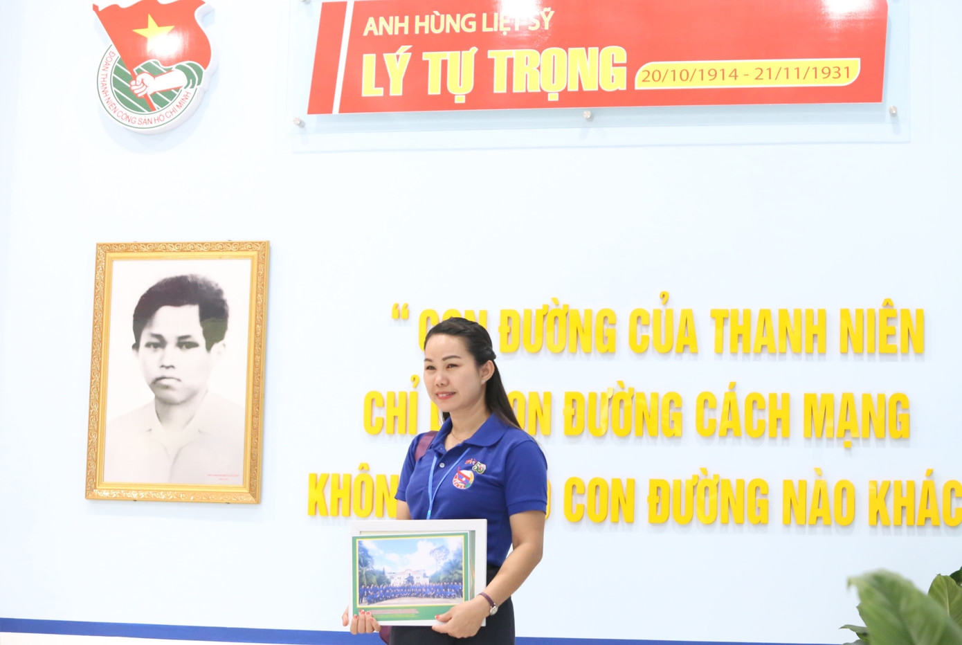 Nữ cán bộ Đoàn nước bạn Lào chụp ảnh lưu niệm với background là câu nói nổi tiếng của Anh hùng liệt sĩ Lý Tự Trọng "Con đường của thanh niên chỉ là con đường cách mạng, không thể có con đường nào khác", trong khuôn viên Phòng truyền thống Trường Đoàn Lý Tự Trọng.