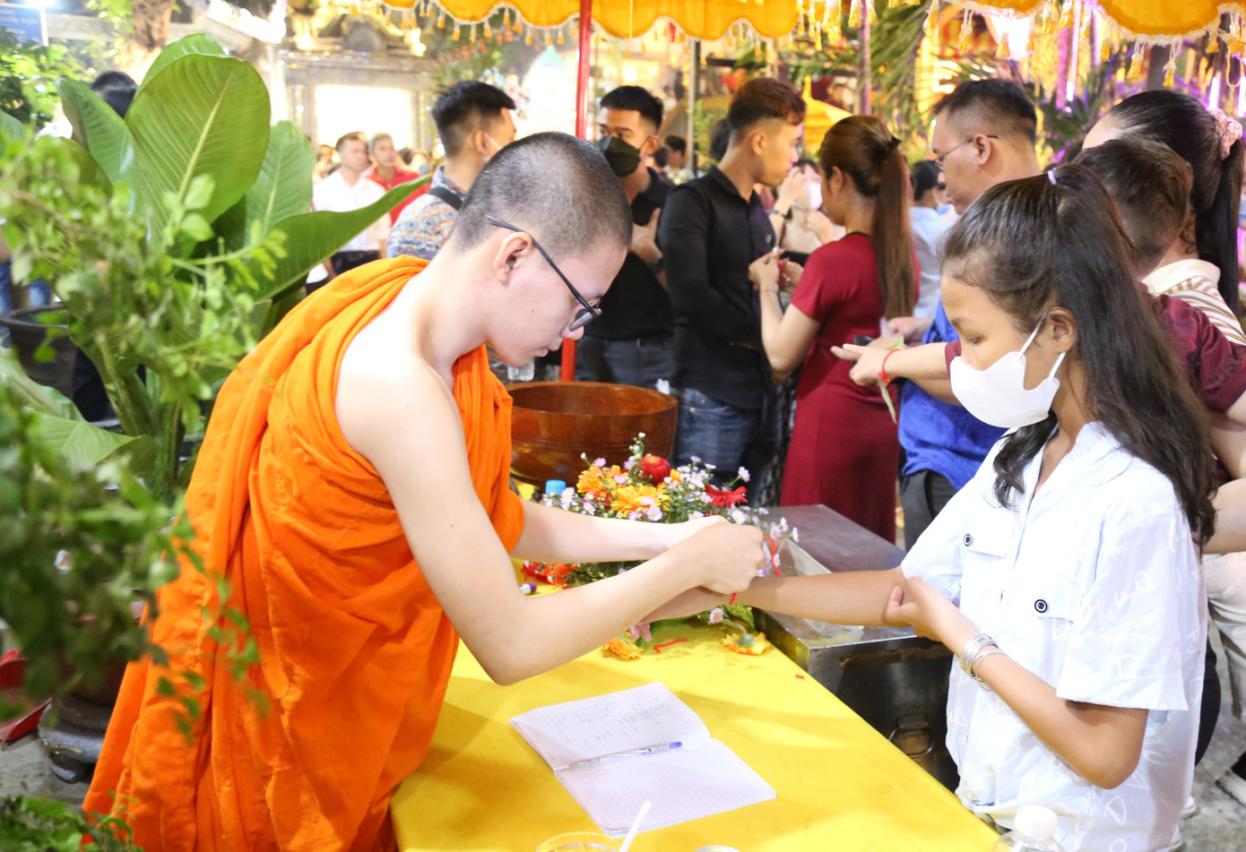 Vị sư nhà chùa buộc chỉ cổ tay cho những người đến chùa.
